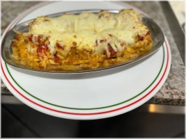 Döner gerold in vers deeg, overgoten met tomatensaus, gesmolten roomboter en kaas. Geserveerd met yoghurt.